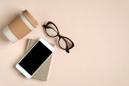 Flat lay feminine home office workspace with paper notepad, glasses, reusable bamboo coffee cup,...