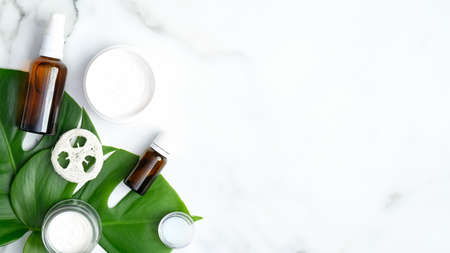 Natural organic SPA cosmetic products set with monstera tropical plant leaves on marble background. Flat lay, top view, copy space. Skin care and beauty treatment conceptの写真素材