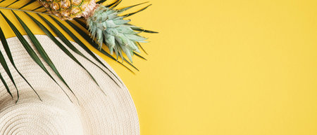 Summer background with fashion beach hat, tropical palm leaf and pineapple. Top view wide banner...