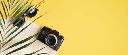 Summer banner template with straw hat, fashion sunglasses, vintage camera. Top view summer background with traveler accessories and tropical palm leaf. Summer holiday vacation, travel, tourism conceptの写真素材