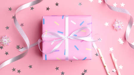 Pink gift box with silver streamers and confetti stars on pastel pink background. Present for girl birthday, Valentines Day, anniversary. Flat lay, top view.の写真素材