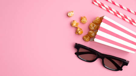 Online cinema art movie watching concept. Flat lay composition with popcorn, 3d glasses and drink straws on pink background. Cinematography concept.の写真素材