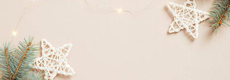 Christmas banner design. Fir tree branches, stars decoration and light garland on pastel beige...