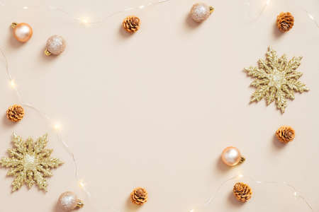 Elegant Christmas flat lay composition. Golden snowflakes, balls, cones, garland on pastel beige background. Minimal, nordic style. Christmas greeting card mockup.の写真素材