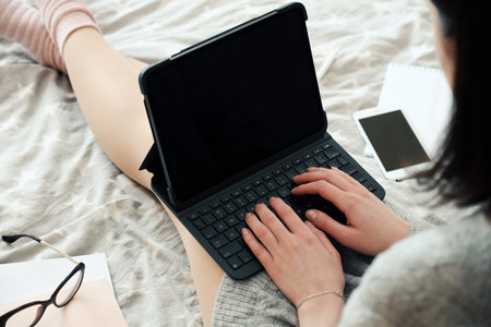 Female freelancer using laptop in bed at home. Working home, stay safe, distance education, online...