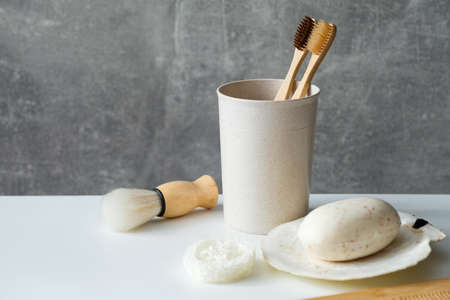 Eco friendly personal hygiene accessories on bathroom table. Natural wooden toothbrushes in holder, shaving brush, homemade soap, hair comb, loofah. Zero waste, plastic free, sustainable lifestyleの写真素材