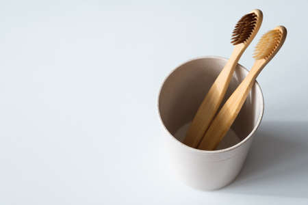 Eco friendly natural bamboo toothbrushes in glass on white background. Biodegradable plastic free bathroom accessory. Zero waste, sustainable lifestyle conceptの写真素材
