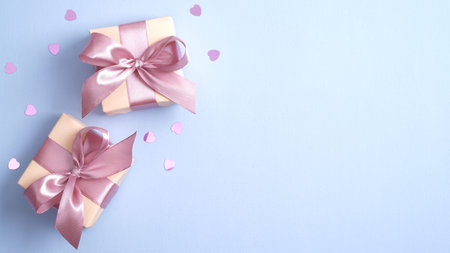 Happy Valentines day concept. Gift boxes with pink ribbon bow on pastel blue background with heart shaped confetti. Valentines day surprise. Banner mockup for Valentines day, Birthday or Mothers Day.の写真素材
