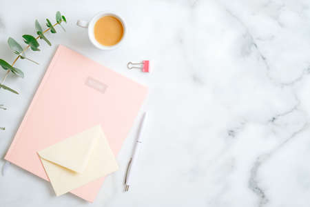 Flat lay home office desk. Female workspace with stylish pink notepad, cup of coffee, eucalyptus leaf, office supplies on marble table. Top view feminine background with copy spaceの写真素材