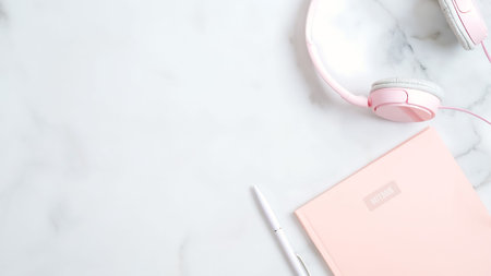 Flat lay home office desk. Women workspace with pink headphones, paper notebook, pen on marble...