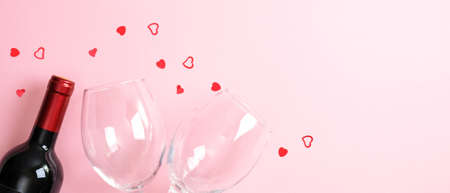 Valentines Day background with bottle of wine champagne, two glasses and heart shaped confetti on pink. Minimal flat lay style composition, top view. Valentines Day, romantic dinner couple conceptの写真素材
