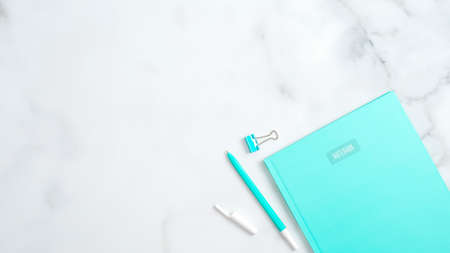 Flat lay mint paper notebook with office supplies on marble background. Modern home office desk table concept. Top view with copy space.の写真素材