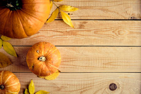 Autumn composition. Pumpkins and yellow leaves on wooden desk.Thanksgiving day or seasonal background. Flat lay, top view, copy space.の写真素材