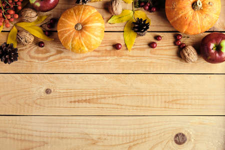 Happy Thanksgiving day concept. Autumn frame made of ripe orange pumpkins, fallen leaves, fruits, nuts on rustic wooden table. Flat lay, view from above.の写真素材