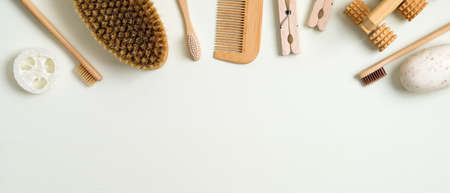 Zero waste bathroom accessories on green background. Frame border of luffa sponge, massage brush, bamboo toothbrushes, hair comb, wooden pins, handmade soap. Eco-friendly bath products, beauty and spaの写真素材