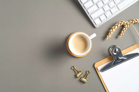 Elegant workspace with coffee cup, computer keyboard, paper clipboard, office stationery, wheat. Flat lay, top view, overhead.の写真素材