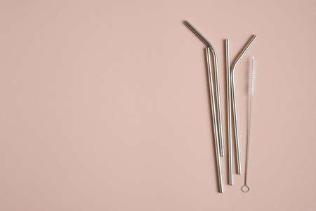 Reusable stainless steel metal drinking straws with cleaning brush on brown background. Flat lay, top view. Zero waste, plastic free concept. Sustainable lifestyle.の写真素材