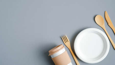 Eco-friendly bamboo cutlery set, paper plate and reusable coffee mug on gray background. Zero waste, plastic free tableware. Sustainable lifestyle concept. Eco shop banner designの写真素材