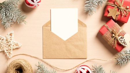 Christmas letter concept. Blank paper card in craft paper envelope, Christmas gifts, wooden...