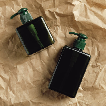 Green pump dispenser bottles on kraft paper. SPA natural cosmetics packaging design, shampoo or soap containers mockups.の写真素材