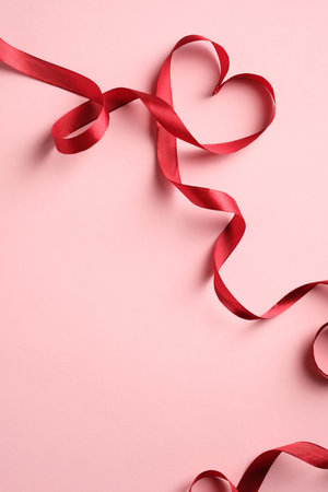 Red Heart shaped ribbon on pink background. Happy Valentine's Day or Mother's Day concept.の写真素材