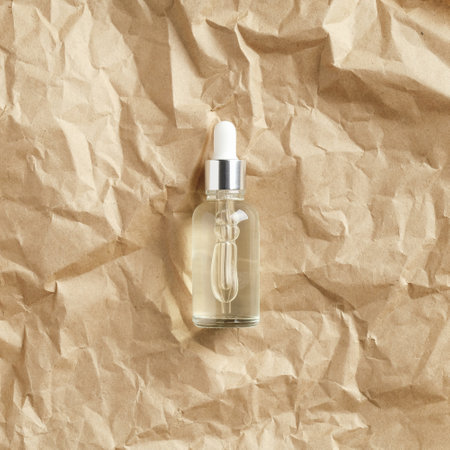 Cosmetic serum in clear dropper bottle on crumpled paper, top view. Natural beauty product packing designの写真素材