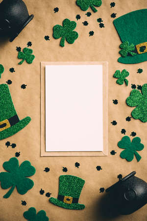 Happy Saint Patrick's day concept. Vertical banner design with greeting card mockup, Irish elf hats, pots of gold, shamrock clover leaves on kraft paper background. Vintage, retro styleの写真素材