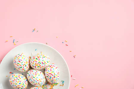 Colorful Easter eggs in plate on pastel pink background. Happy Easter concept. Flat lay, top view, copy space. Minimal style.の写真素材