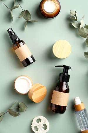 SPA herbal cosmetics set and eucalyptus leaves on green background. Natural organic beauty products design, branding. Flat lay, top view.の写真素材