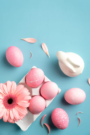 Easter flat lay composition with pink Easter eggs, spring flower, Easter bunny rabbit on turquoise...