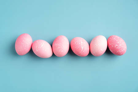 Row of pink Easter eggs on turquoise background. Happy Easter minimal concept. Flat lay, top view.の写真素材