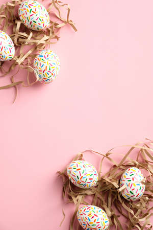 Easter vertical banner mockup. Frame made of colorful speckled Easter eggs in nests on pink background. Flat lay, top view, copy space.の写真素材