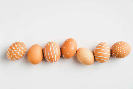 Painted Easter eggs in row on white background. Flat lay, top view. Elegant, simple, modern style.の写真素材