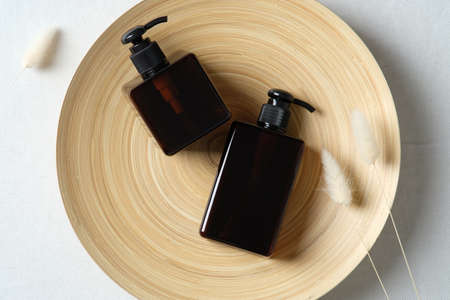 Natural skincare SPA cosmetics bottles and dried flowers on plate. Dark amber glass containers of shampoo or liquid soap. Flat lay. Top view.の写真素材