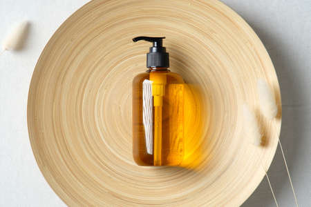 Organic natural cosmetic product and dried flowers on plate. Amber glass dispenser bottle. SPA beauty product packaging design.の写真素材