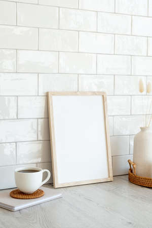 Picture frame mockup, cup of coffee, vase of dried flowers on wooden table. Nordic, Scandinavian style still life. Home interior design.の写真素材