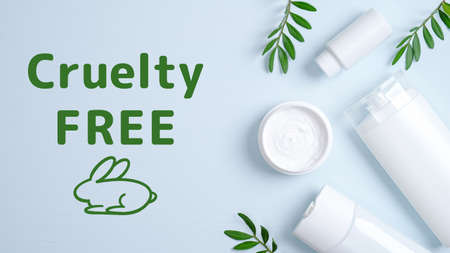 Cruelty free cosmetics set on blue background. Hair care herbal cream in jar, shampoo bottle, shower gel container and green leaves. No animal testingの写真素材