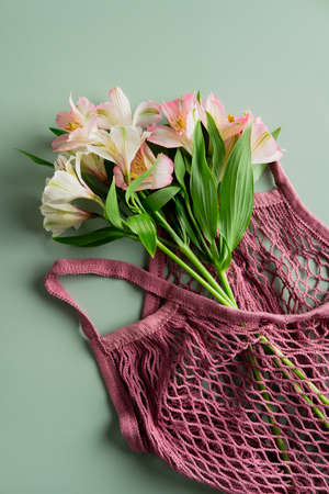 Grocery bag with spring flower on green background. Sustainable lifestyle, fashion concept.の写真素材