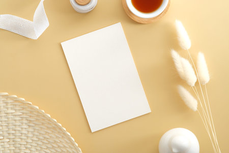 White invitation card mockup, coffee cup, dried flowers, ribbon, decor on beige background. Flat lay, top view. Wedding invite design.の写真素材