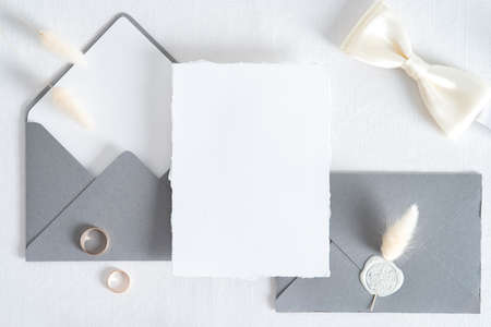 Wedding invitation card template. Flatlay blank paper card, gray envelopes, goled rings on white background. Vintage style. Top view.の写真素材