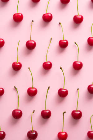 Cherry pattern on pink background. Flat lay, top view red ripe berries on table.の写真素材