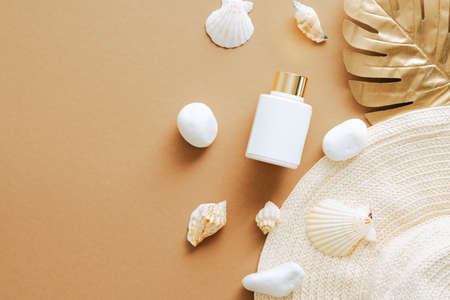 Sunscreen lotion, seashells, straw hat on sandy color background. Flay lay, top view. Luxury suntan cream design.の写真素材