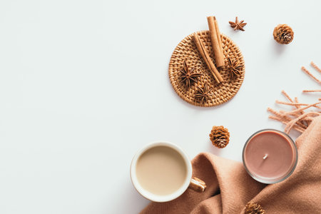 Cozy home desk table with coffee cup, candle, plaid, cinnamon sticks on white background. Autumn,...