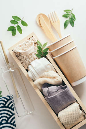 Eco-friendly utensil and different shopping bags in wooden box on white background. Zero waste, plastic free products set.の写真素材
