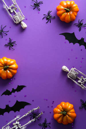 Happy Halloween poster mockup. Flat lay pumpkins, scary skeletons, bat silhouettes on purple background. Top view, overhead.の写真素材