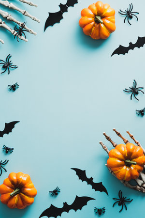 Happy Halloween holiday concept. Frame made of pumpkins, skeleton hands, bats, spiders on blue background. Flat lay, top view, overhead.の写真素材