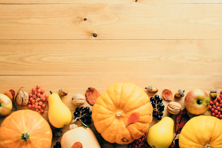 Happy Thanksgiving day card. Frame made of pumpkins, red berries, pine cones, walnuts, apples on wooden table. Autumn fall background. Flat lay, top view, copy space.の写真素材