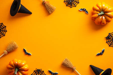 Halloween greeting card mockup. Halloween decorations, pumpkins, witches hats, bats on orange background. Flat lay, top view, copy space. Halloween layout, party invitation flyer design.の写真素材