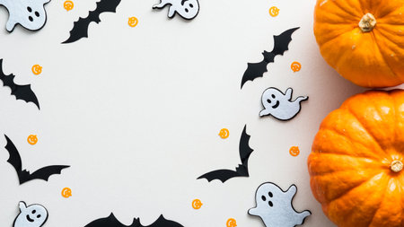 Halloween background with cute decorations and pumpkins on white table. Flat lay, top view, copy...