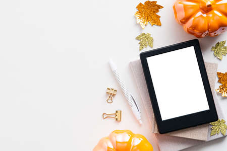 Autumn background with digital tablet ebook mockup, pumpkins, maple leaves on white table. Flat lay, top view.の写真素材